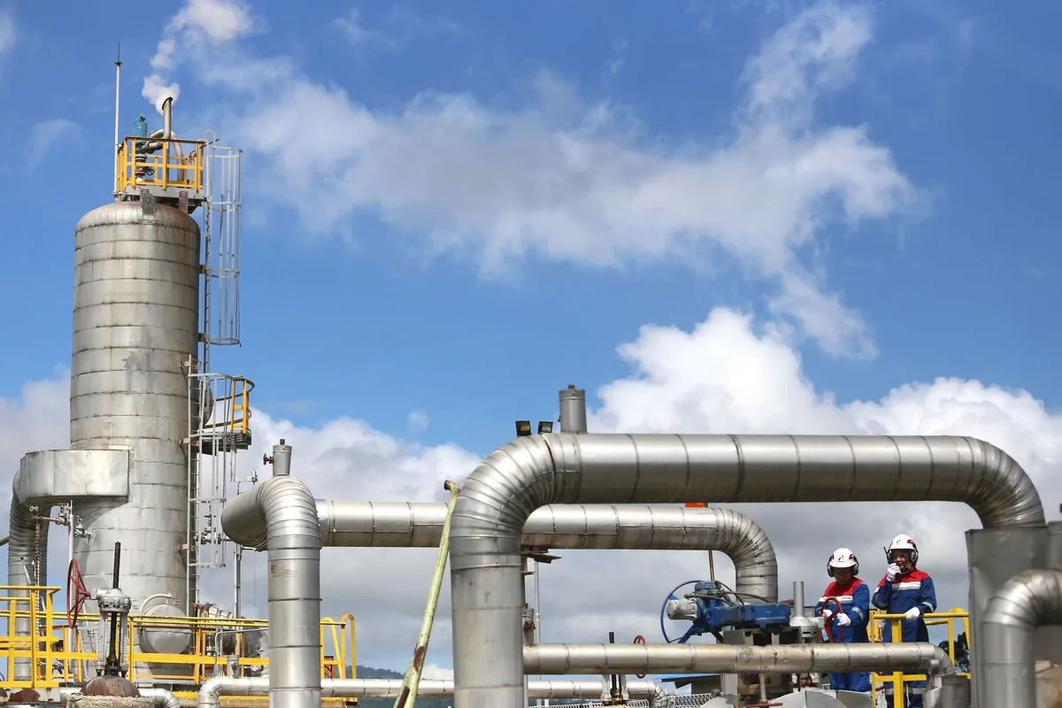 Endüstriyel gaz tesisindeki büyük boru hatları ve platform üzerinde çalışan saha ekibi